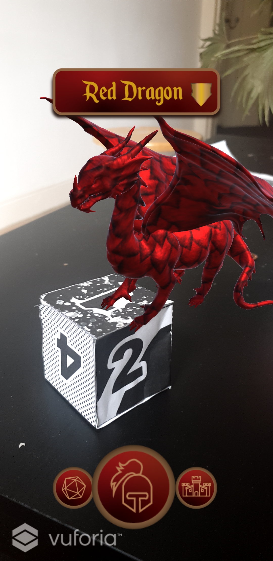 Photograph of dice with 3d model of dragon projected to the top of it. UI shows enlarged centre circle button with an armor icon, and two smaller circle buttons with icons of dice and a castle